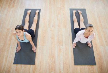 İki genç kadın paspaslar zor germe ve esneklik egzersiz yoga egzersiz sırasında pratik yerleştirmek