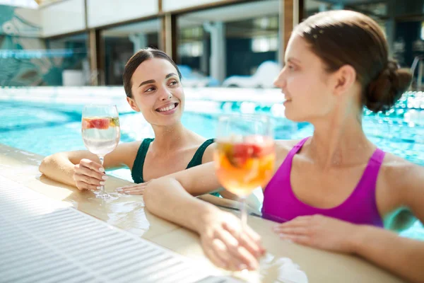 Two Cheerful Females Swimsuits Having Cocktails Talking While Sitting Water — Stock Photo, Image