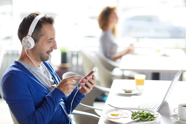 Sorrindo Homem Bonito Azul Casaco Sentado Mesa Usando Smartphone Enquanto — Fotografia de Stock