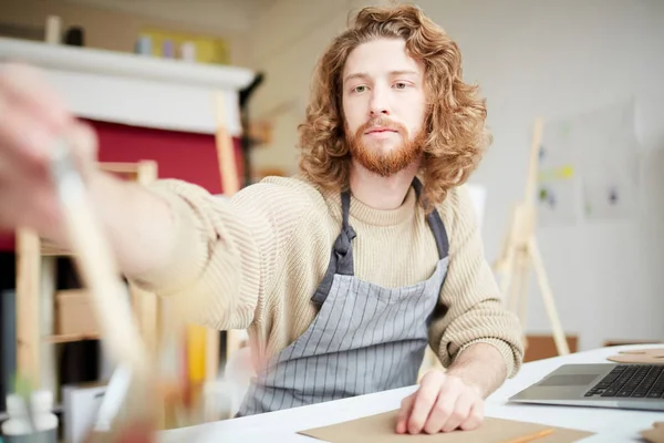 若いですひげを生やした男取る鉛筆前に作るスケッチでノートパッド中作業でスタジオ — ストック写真