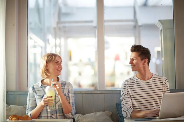 隣のテーブルでカフェに座って 話をしてカクテルを持つラップトップと女の子と幸せな男 — ストック写真