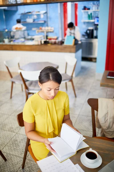 Mujer Joven Vestido Amarillo Sentada Junto Mesa Leyendo Libro Tomando —  Fotos de Stock