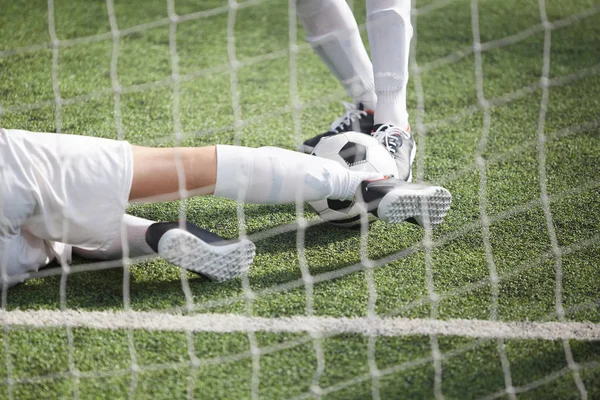 ネットの後ろに緑のフィールドでの試合中にサッカー ボールを追求 つのサッカー選手の足 — ストック写真