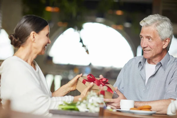 在咖啡馆吃饭时 老人和女人一边看着对方 一边给人吃礼品盒 — 图库照片