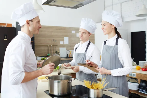 Vrolijke Zelfverzekerde Stagiairs Uniformen Glimlachen Terwijl Met Een Professionele Kok — Stockfoto