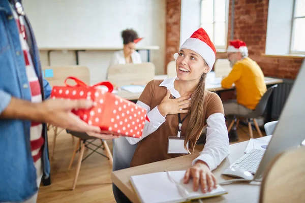 Erstauntes Mädchen Mit Weihnachtsmütze Schaut Kollegin Die Ihr Rotes Paket — Stockfoto