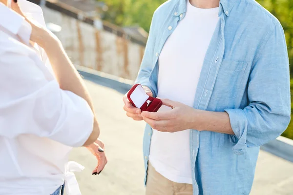 穿着休闲服装的男子手持订婚戒指的首饰盒 并向屋顶上的女朋友求婚 — 图库照片