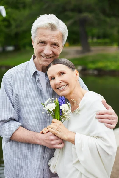 快乐的老人拥抱妻子 两人在公园散步时都看着镜头 — 图库照片