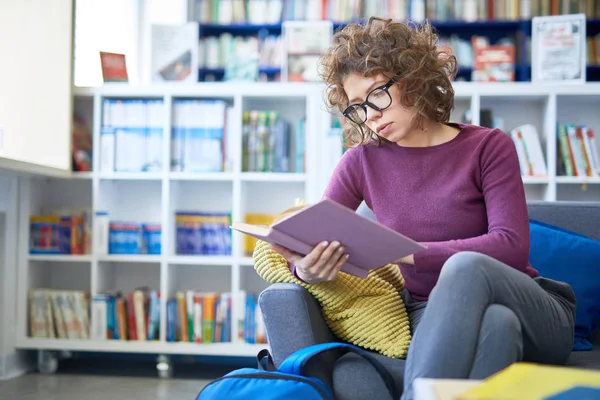 Dziewczyna Wchłania Się Czytanie Książki Siedząc Kanapie Bibliotece — Zdjęcie stockowe