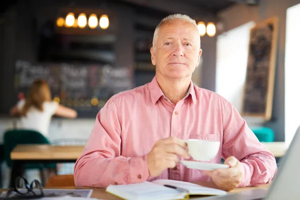 コーヒー ブレークで仕事を計画しながらカフェでテーブルに座ってお茶と深刻な年配の男性 — ストック写真