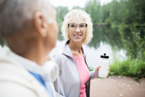 快乐成熟活跃的女性与一瓶水与她的丈夫交谈后 早上锻炼户外 — 图库照片