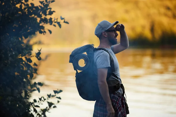 湖の近くに立って景色を眺めながらリュックを持つ若い観光客 — ストック写真