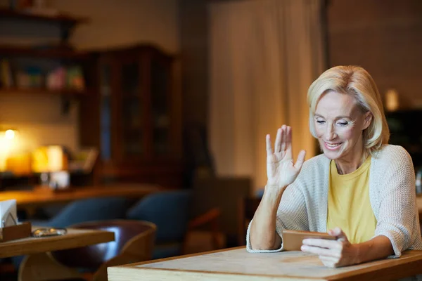 Элегантная Зрелая Блондинка Машет Рукой Разговаривая Через Видео Чат Смартфоне — стоковое фото