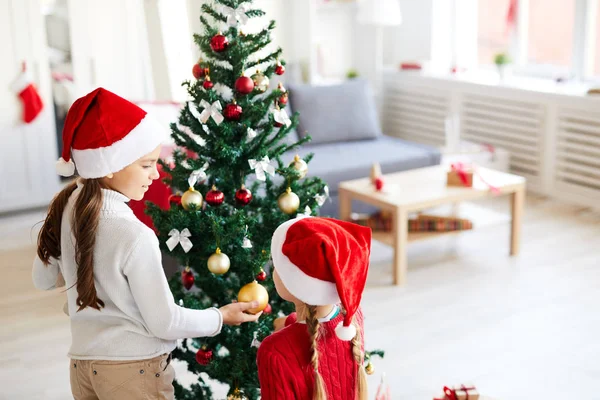 Eines Der Süßen Weihnachtsmädchen Zeigt Ihrem Geschwister Goldene Kugel Auf — Stockfoto