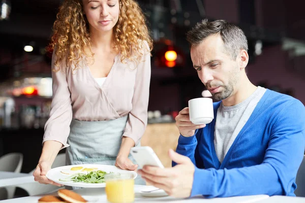 Hombre Ocupado Bebiendo Café Desplazándose Teléfono Inteligente Mientras Camarera Trae — Foto de Stock