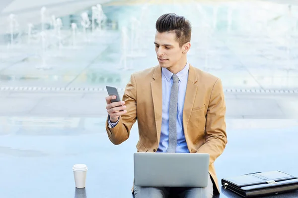 优雅的员工或企业家在智能手机上阅读信息 坐在笔记本电脑前的喷泉旁 — 图库照片