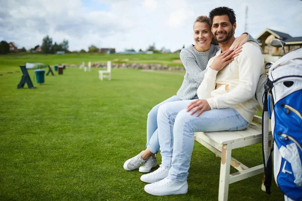 Young Casual Affectionate Couple Sitting Bench Green Court Golf Playing — Stock Photo, Image
