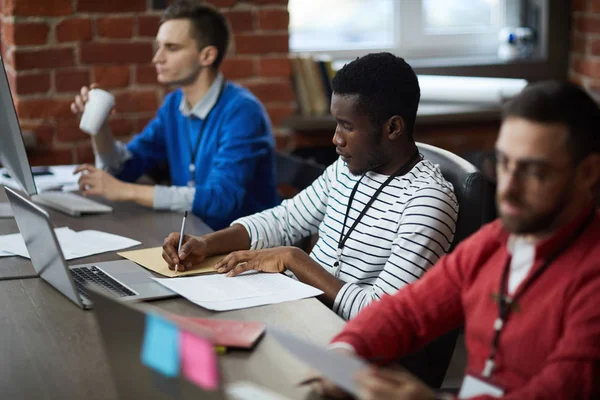 Drei Mitarbeiter Sitzen Hintereinander Schreibtisch Einer Von Ihnen Macht Notizen — Stockfoto