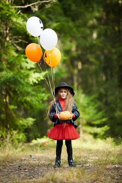 Dziewczynka Stroju Halloween Trzymając Dojrzałą Dynię Pęczek Balonów Stojąc Ścieżce — Zdjęcie stockowe