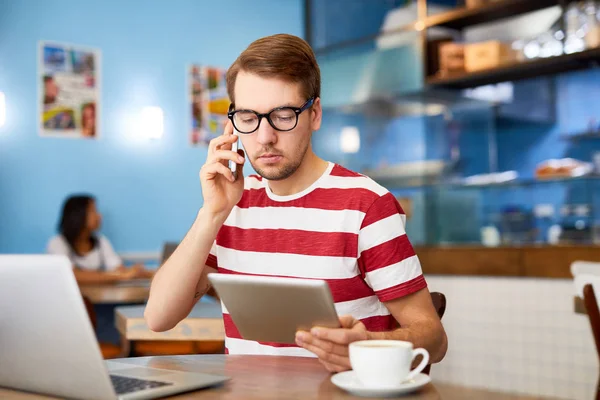 Beschäftigter Junger Mann Freizeitkleidung Sitzt Tisch Mit Laptop Davor Spricht — Stockfoto