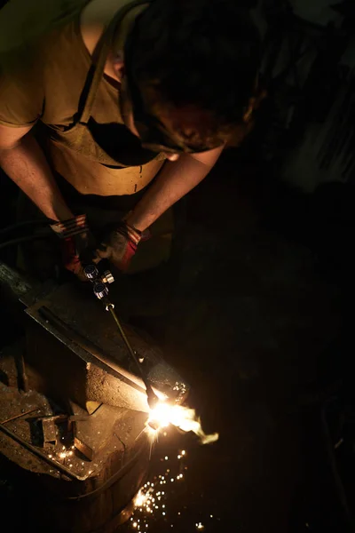 アンビルと溶接ワークによって立って作業服の若い鍛冶屋の専門家 — ストック写真