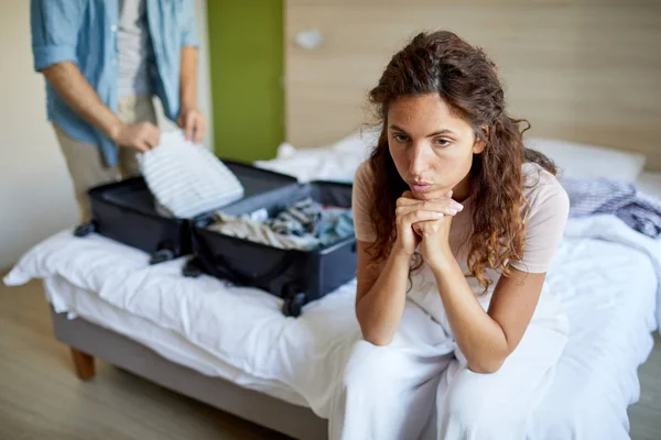 Stressato Giovane Donna Seduta Sul Letto Mentre Marito Prepara Valigia — Foto Stock