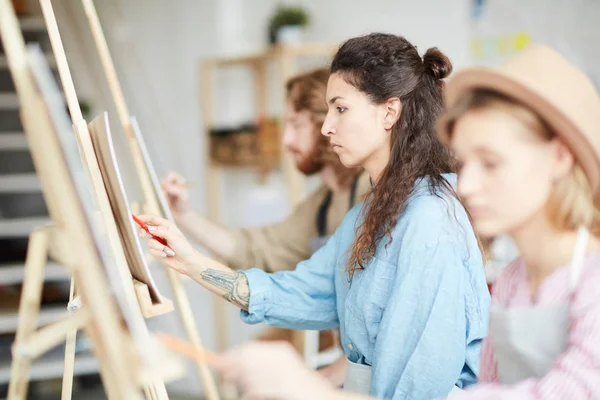 Chica Seria Concentrándose Trabajo Pintura Mientras Está Sentada Frente Caballete — Foto de Stock