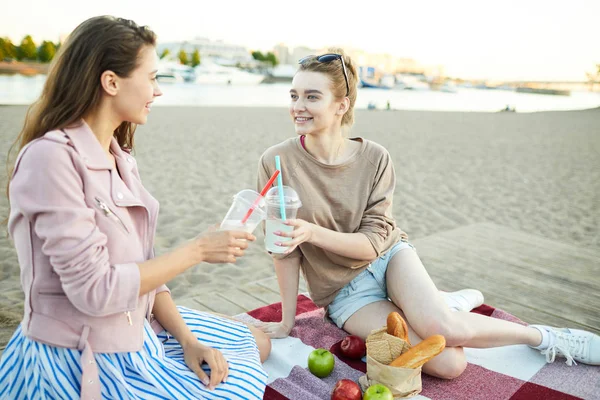 海辺の格子に座りながら スタイリッシュなカジュアルウェアで乾杯する2人の女の子 — ストック写真