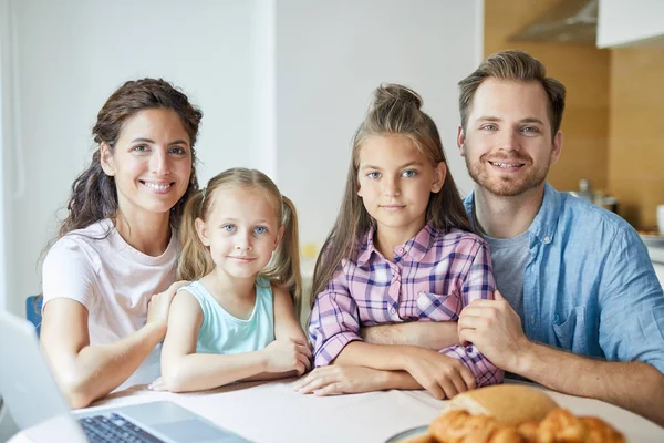健康的年轻家庭的父母和两个女儿坐在餐桌后 而呆在家里 — 图库照片
