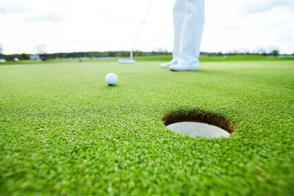 距離に地面にボールと穴を打つ前に ゴルフ選手の足 — ストック写真