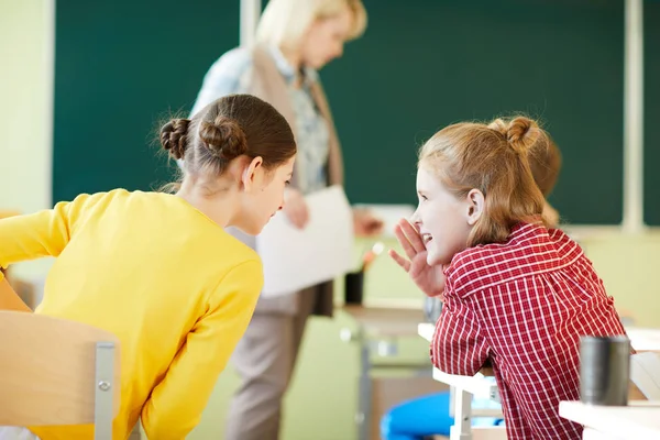 Χαρούμενες Μαθήτριες Που Κάθονται Στα Γραφεία Και Μιλούν Ενώ Κουτσομπολεύουν — Φωτογραφία Αρχείου