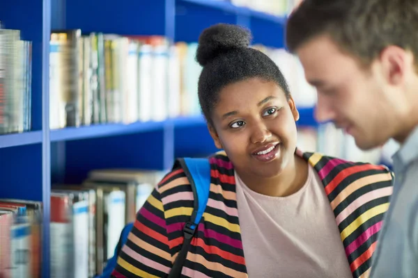 Afrykańska Studentka Rozmawia Swoim Przyjacielem Podczas Szukania Książki Bibliotece — Zdjęcie stockowe