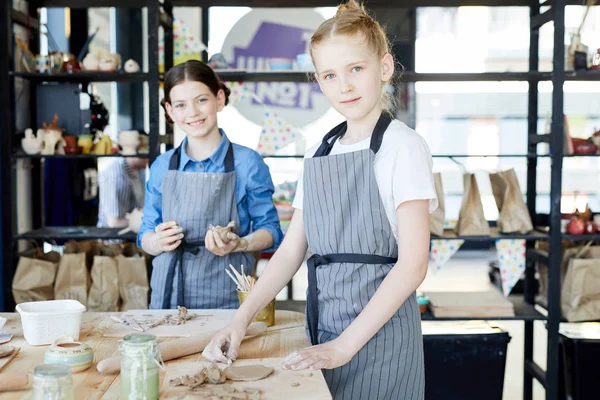 柔らかい粘土で作業しながらテーブルのそばに立っている2人のかわいい女の子が陶器を作る — ストック写真