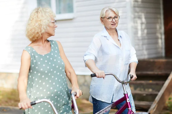 Dos Mujeres Maduras Activas Con Bicicletas Conversando Mientras Relajan Día — Foto de Stock