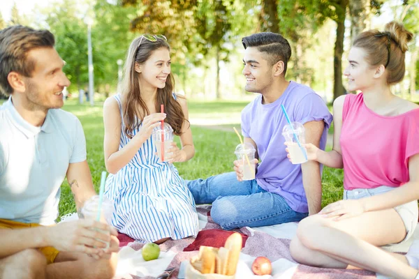 Grupo Adolescentes Felices Sentados Césped Tomando Bebidas Durante Picnic Día —  Fotos de Stock