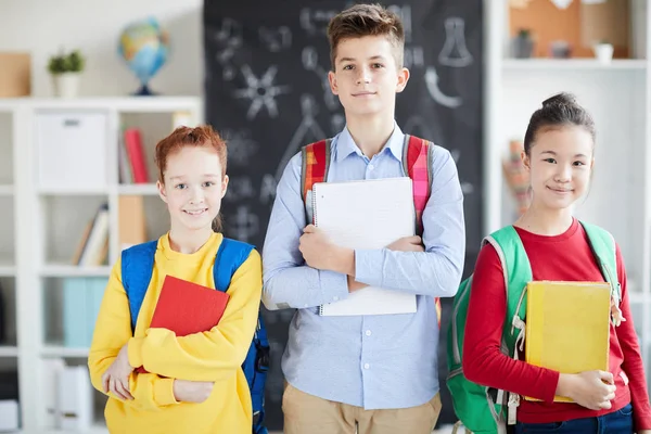 Grupp Två Vackra Skolflickor Och Smart Skolpojke Med Böcker Stående — Stockfoto