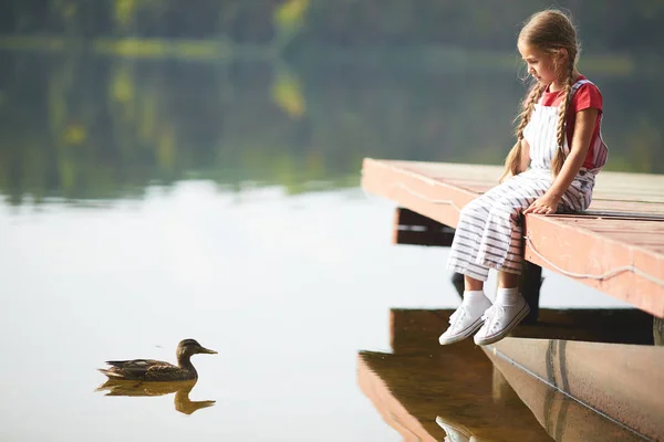 Menina Repousante Olhando Pato Flutuando Direção Ela Enquanto Sentado Pontão — Fotografia de Stock