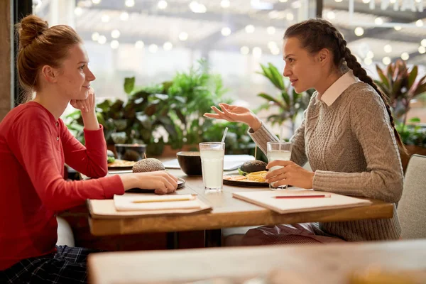 昼食でファーストフードカフェで会話をするカジュアルウェアの2人の十代の女の子 — ストック写真