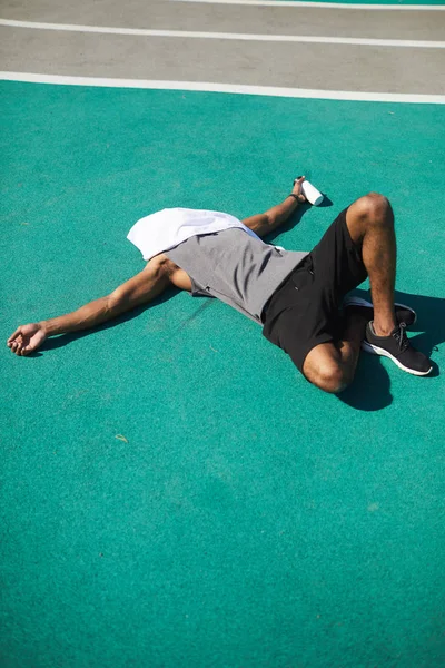 Irreconhecível Exausto Jovem Negro Com Toalha Rosto Deitado Chão Estádio — Fotografia de Stock
