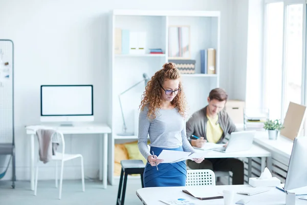 Ung Casual Manager Tittar Igenom Papper När Står Vid Skrivbordet — Stockfoto