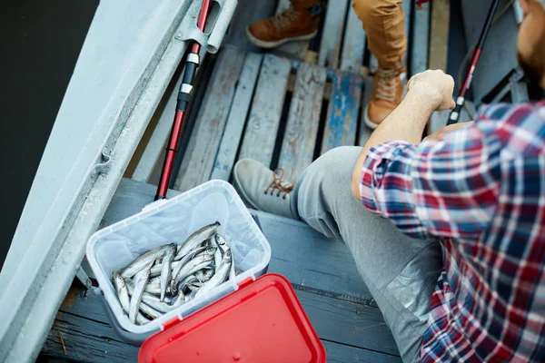 2人の漁師が近くに座っているボートのプラスチック容器またはバケツの新鮮なアンチョビの山 — ストック写真