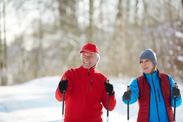 トレッキングやレジャーで森のスキー冬のスポーツで幸せな熟年カップル — ストック写真