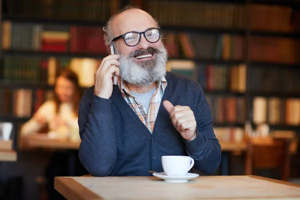 愉快的资深男子在眼镜和休闲服装说话的智能手机和有一杯茶在咖啡馆 — 图库照片