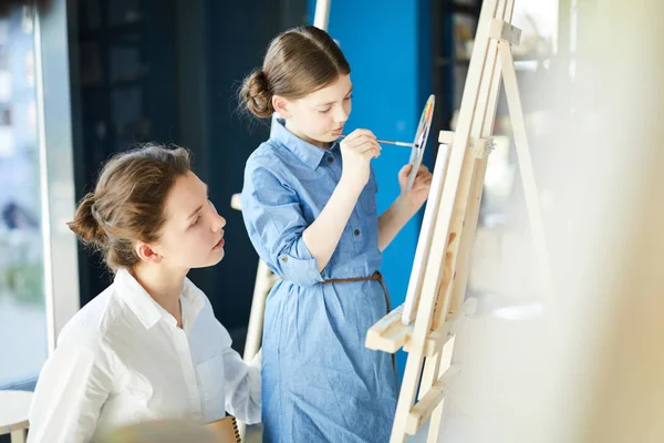 Young Teacher Standing One Pupils Looking Easel Her Painting — Stock Photo, Image