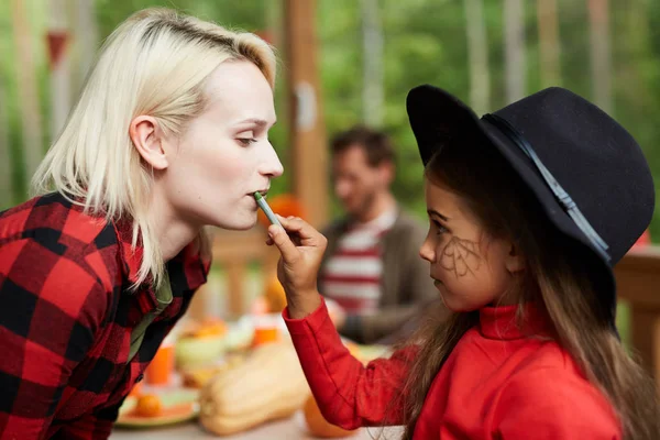 Mała Czarownica Stosowanie Szminki Jej Wargi Matki Podczas Robienia Halloween — Zdjęcie stockowe