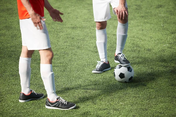 两名年轻足球运动员站在绿地上讨论比赛要点 — 图库照片