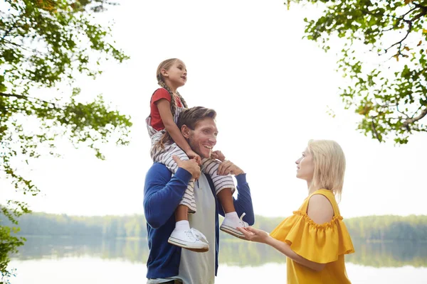 田舎の水辺で夏の週末を楽しむ3人の若い安らかな家族 — ストック写真