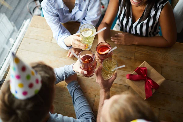 木製のテーブルの上に誕生日のための乾杯の間に友人のグループによって保持されたメガネの飲み物の概要 — ストック写真