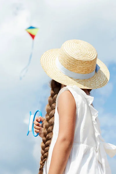 凧遊びながら曇った空を見つめ 帽子と青いドレスを着たかわいい女の子のバックビュー — ストック写真