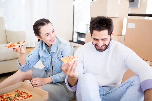 年轻的笑夫妇在吃比萨饼的时候玩得很开心 然后搬迁到新的房子 — 图库照片